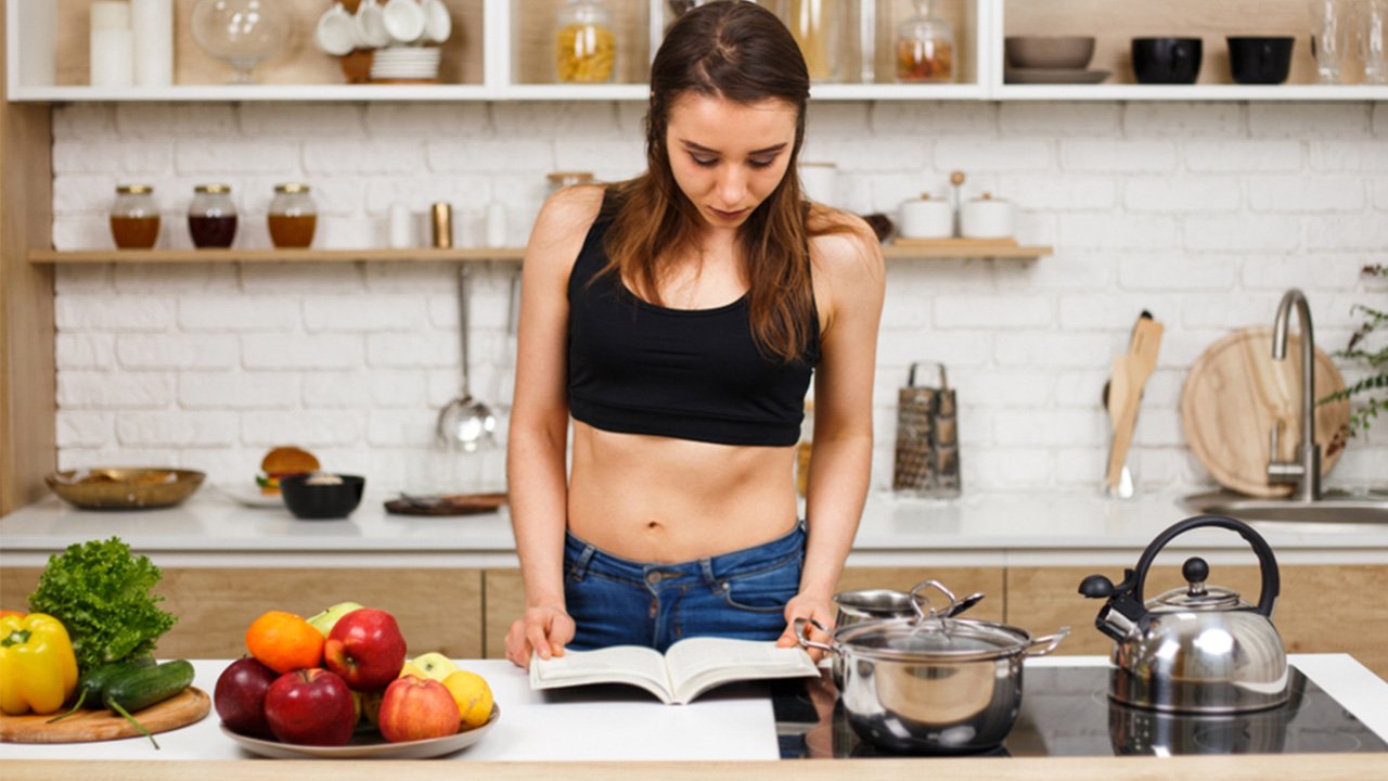 woman looking at a keto cookbook in kitchen