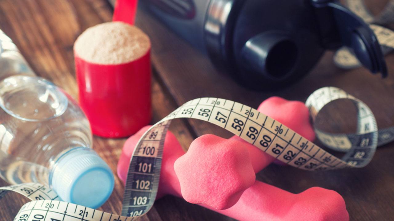 dumbbells, protein powder, and waist measuring tape