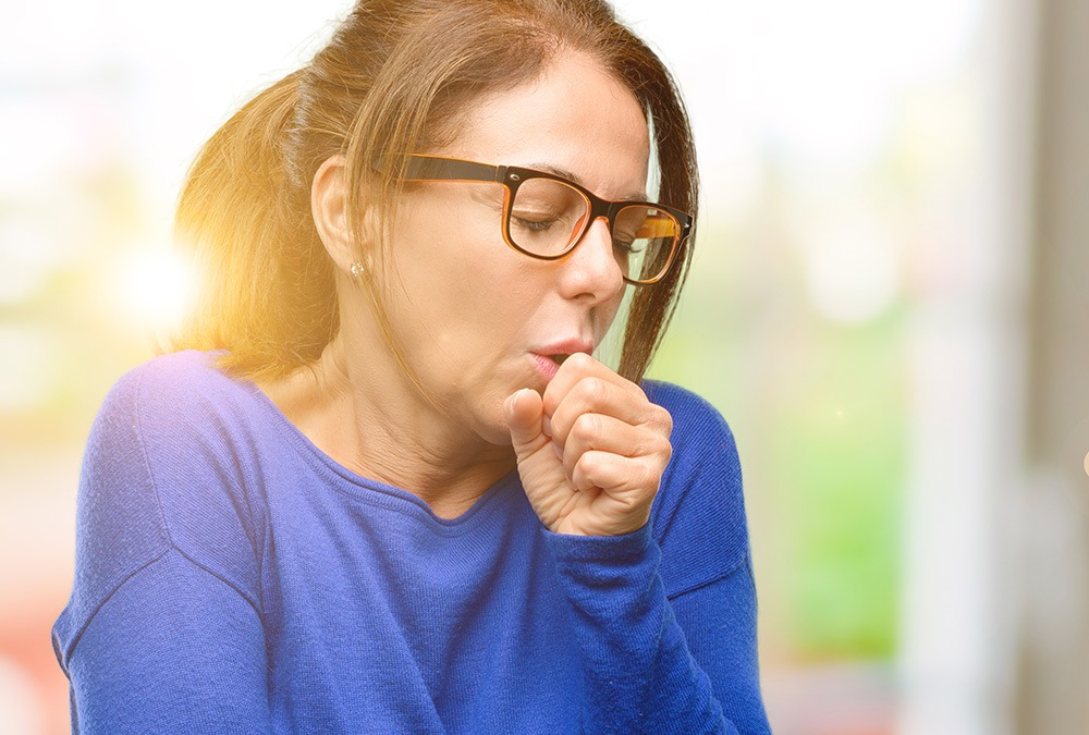 woman with glasses coughing due to tonsil stones