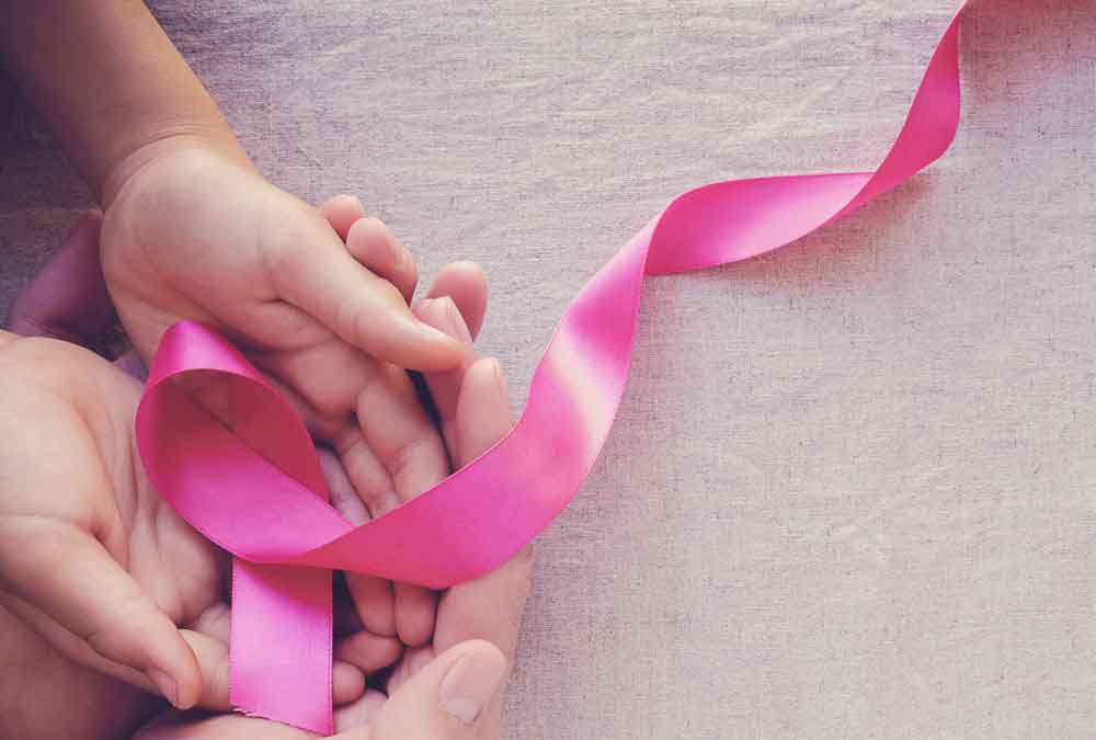 mom holding newborn baby hands with pink ribbon