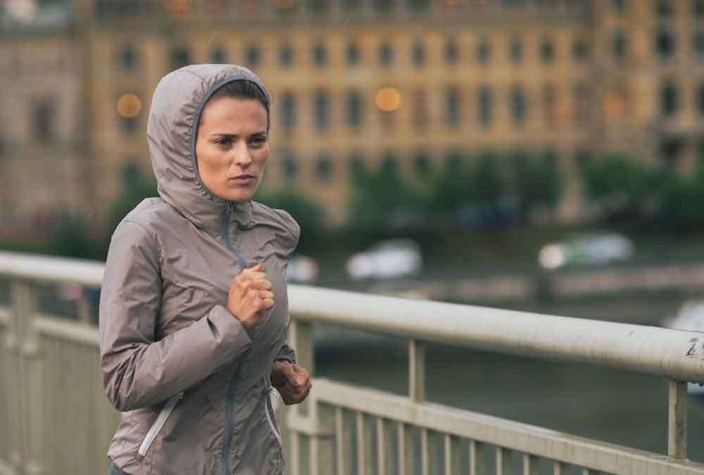 lady jogging with hoody over bridge