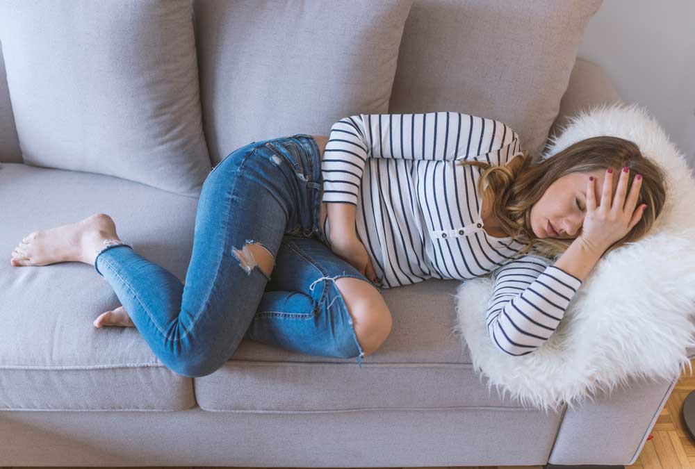 lady with stomach ache lying on couch