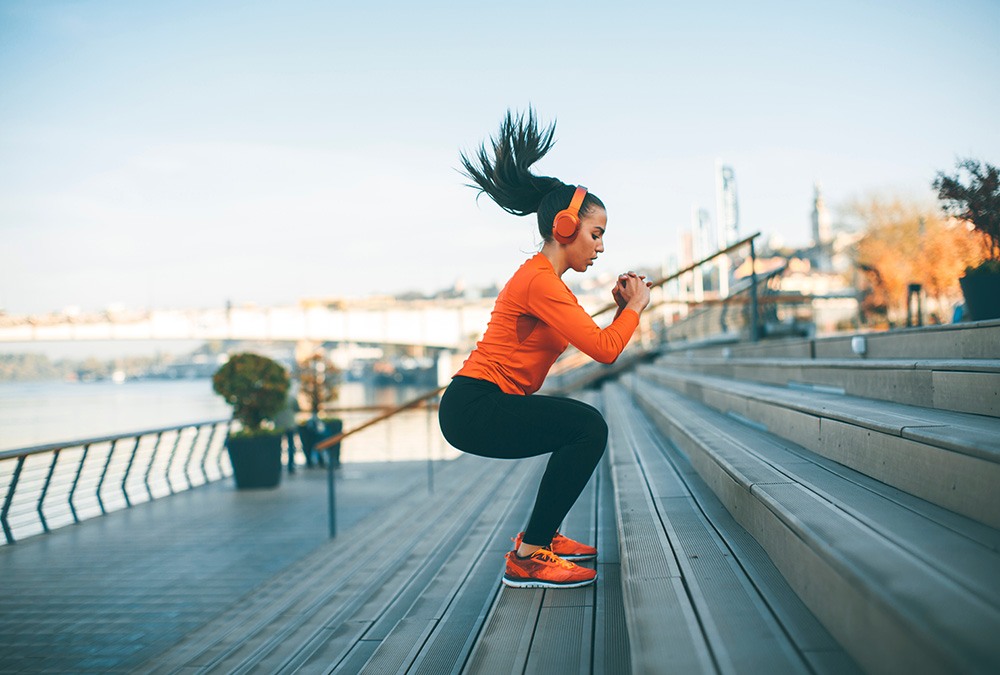 woman in orange jumping up stairs workout