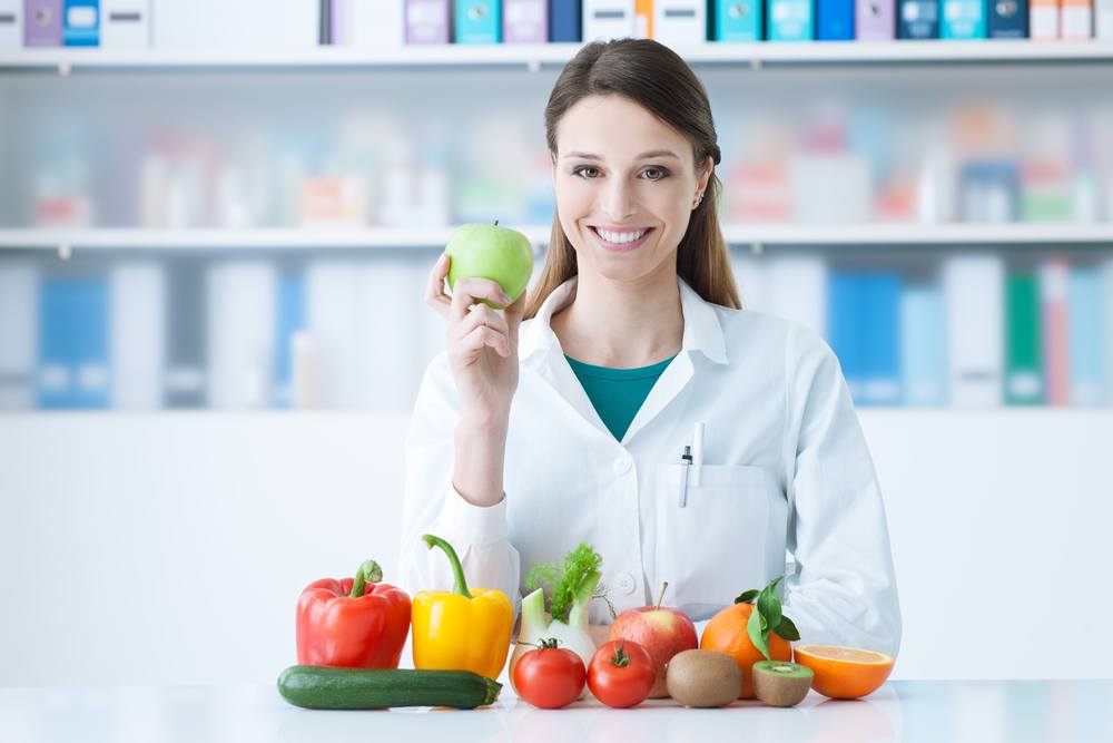 smiling female doctor holding a green apple