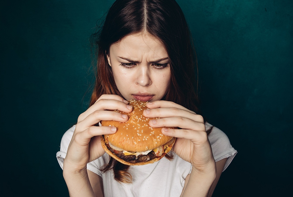 girl looking frustrated looking at cheesburger