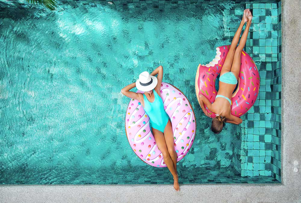 2 women lounging in pool on doughnut inflatables