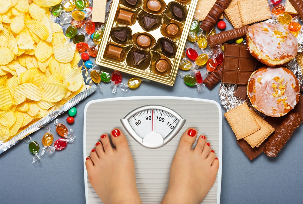 lady standing on weight scale looking at junk food