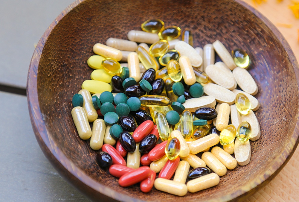 colorful pills and tablet in a wooden bowl