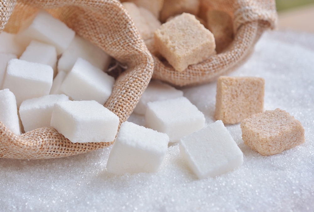 white and brown sugar cubes spilled from burlap bag