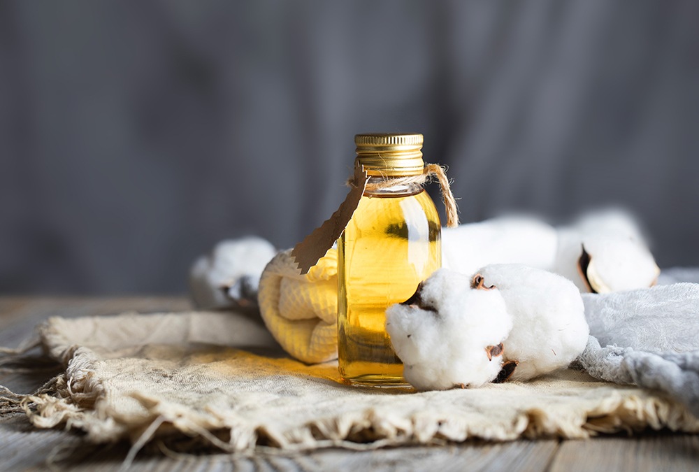 Cottonseed oil in a small bottle and some cotton on the side