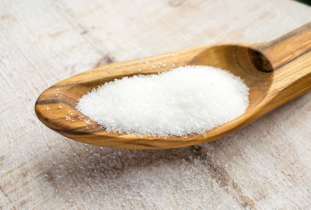white sugar granules in a wooden spoon