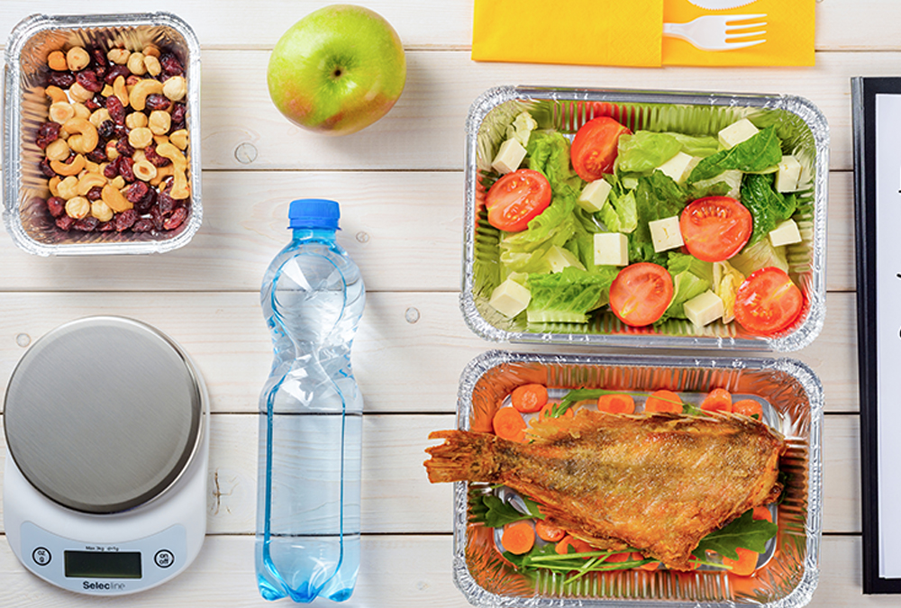 bottled water, apple and healthy meals in foil trays