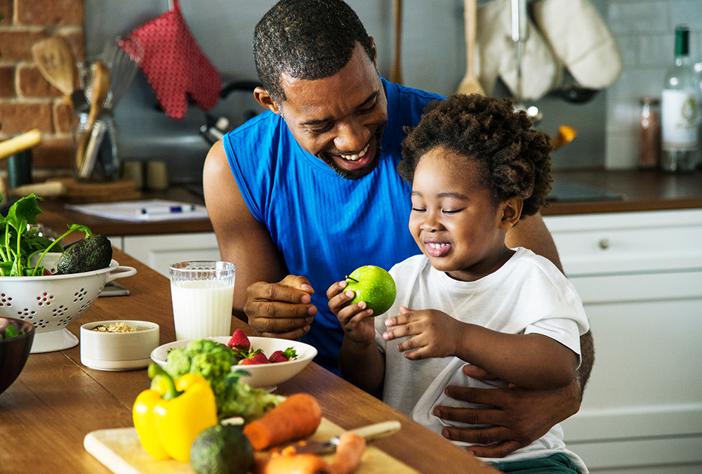 father and toddler sitting infromt of dining table with healthy foods